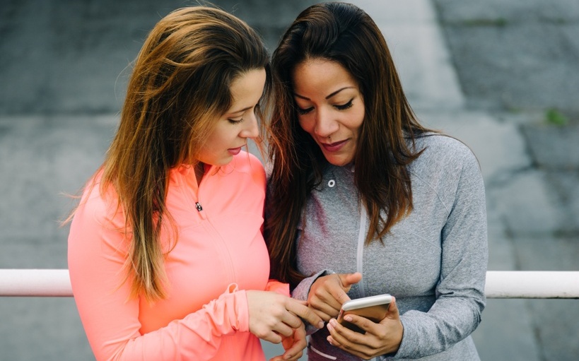Urban fitness women checking training with smartphone app